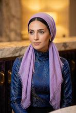 Load image into Gallery viewer, A dusty purple scarf with frayed edges, tied in a loose knot, laid flat on a light brown wooden floor.