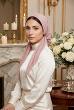 Load image into Gallery viewer, A woman wearing a dusty pink dotted hijab and a cream-colored long-sleeve dress, posed in an elegant room with a marble fireplace, candles, and a white rose bouquet.