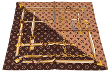 Load image into Gallery viewer, A luxury fashion scarf featuring a brown and beige monogram pattern overlaid with a gold chain-link illustration and small circular medallions, shown flat against a white background.