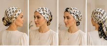 Load image into Gallery viewer, A collage showing a woman modeling a black and white monogram patterned headscarf in multiple ways, with a large full-look view on the left and nine smaller labeled views on the right showing different styles such as classic wrap, side drape, low knot, turban knot, rosette bun, sleek underwrap, twist headband, fully covered, back view, left side, and right side.
