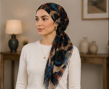 Load image into Gallery viewer, A scarf with an abstract painterly pattern in navy, teal, rust, and beige, shown both flat on a wall and modeled by a woman wearing it as a headscarf.
